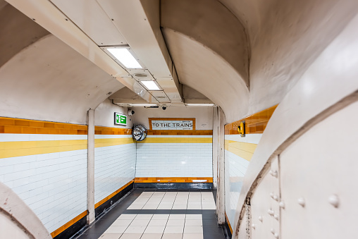 London, UK tube station underground corridor hallway with nobody and sign direction for to the trains with yellow orange colors