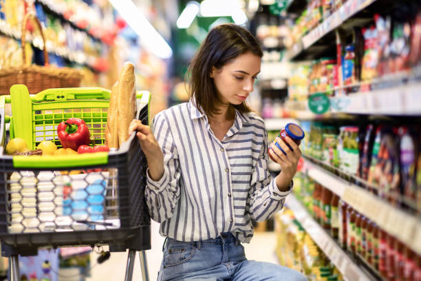 молодая женщина с тележкой покупки в гипермаркете - supermarket shopping retail choice стоковые фото и изображения