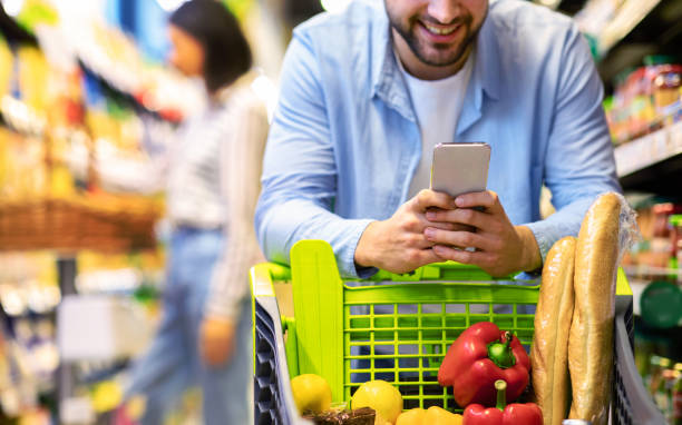 istock Guy with mobile phone shopping at super market 1305346828