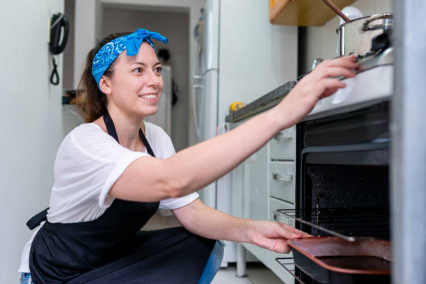 istock Young cook in her apartment's kitchen putting cake dough in the oven 1305347009