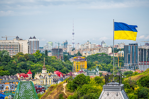 Kyiv, Ukraine cityscape of Kiev and Ukrainian flag waving in the wind during summer in Podil district and colorful new buildings