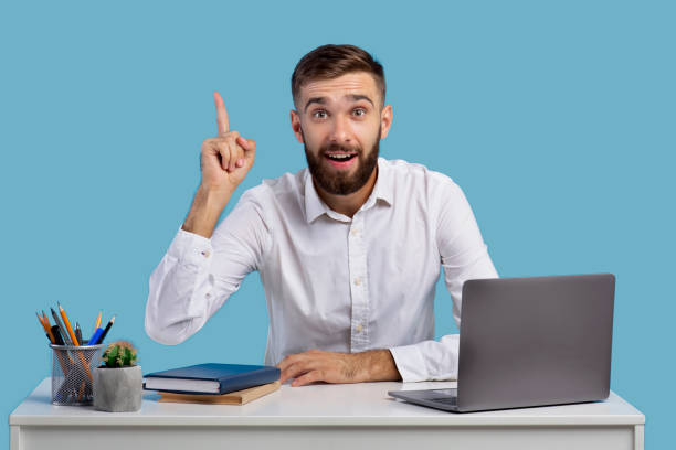 istock Millennial Caucasian office worker having creative idea, gesturing eureka at workplace on blue studio background 1305348703