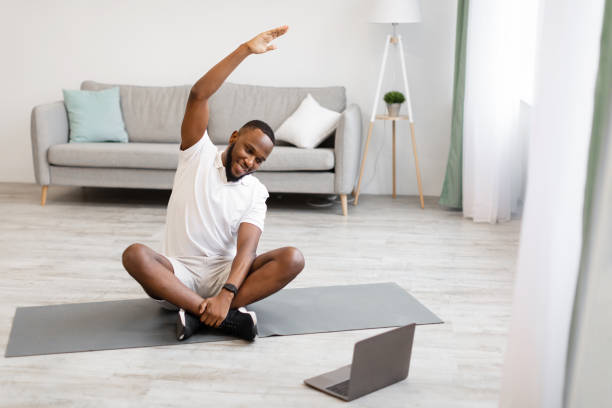 istock African Sporty Guy At Laptop Doing Stretching Exercise At Home 1305349499