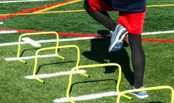 istock Athlete stepping over yellow mini hurdles on a turf field 1305349729