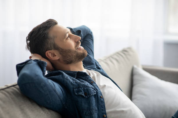 istock Handsome middle-aged man relaxing on sofa at home 1305350146