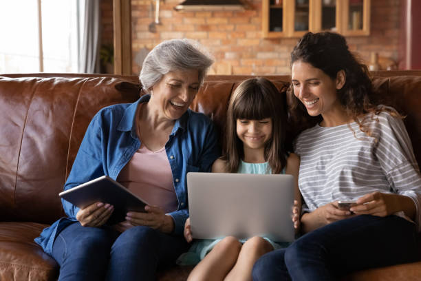 istock Happy three generations of women relax on couch with gadgets 1305351018