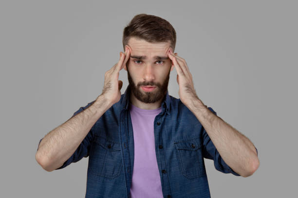 istock Young man having terrible headache, suffering from migraine on grey studio background 1305351028