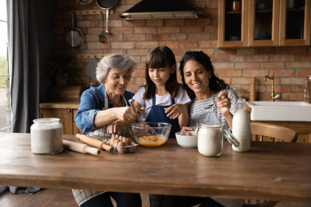 glückliche drei generationen von frauen kochen zusammen - grandmother cooking baking family stock-fotos und bilder