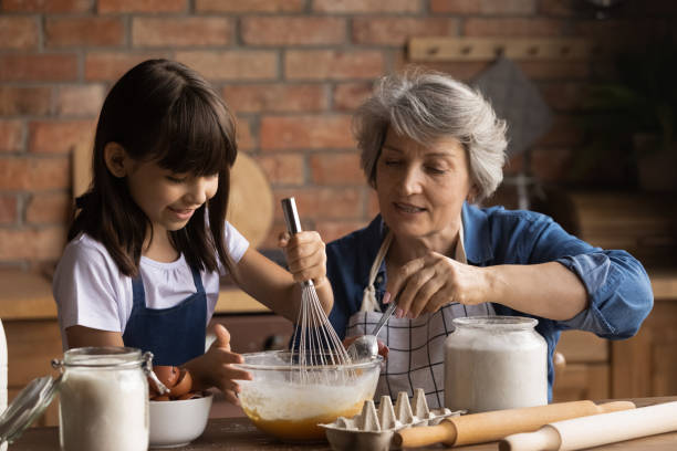 feliz abuela mayor y pequeña nieta cocinan juntos - baking food cookie breakfast fotografías e imágenes de stock