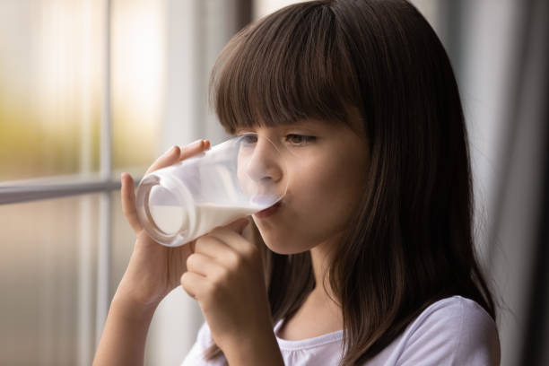 le petit enfant de fille se sentent le lait savoureux de boisson assoiffée - milk child drinking little girls photos et images de collection