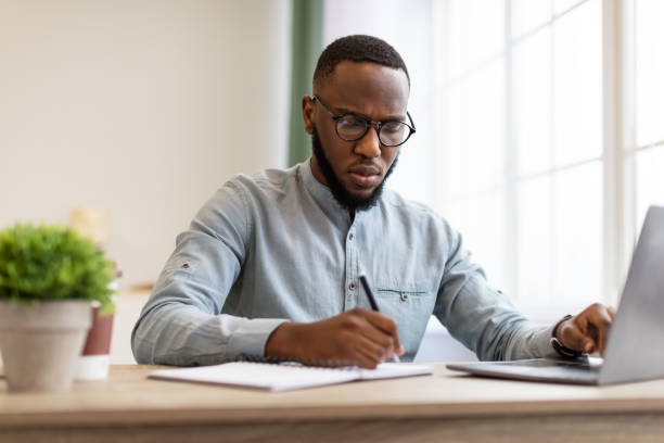 istock Black Businessman Taking Notes Sitting Working At Workplace In Office 1305351337