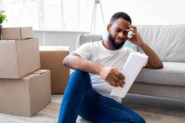 istock Frustrated African Man Reading Bill Sitting Among Moving Boxes Indoor 1305351676