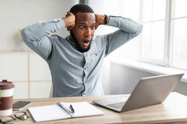istock Shocked African Businessman Having Issue Working On Laptop In Office 1305352386