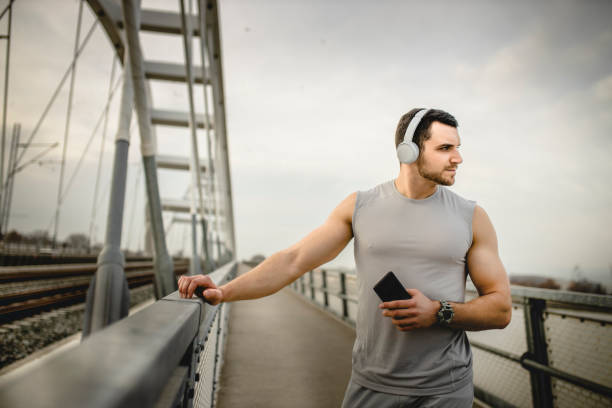 istock Man using wireless headphones while running outdoors 1305352687