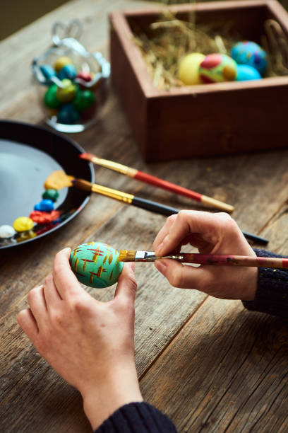 istock Female preparing for religious holiday Easter, dyeing eggs with paintbrush. Artist's workshop 1305352848