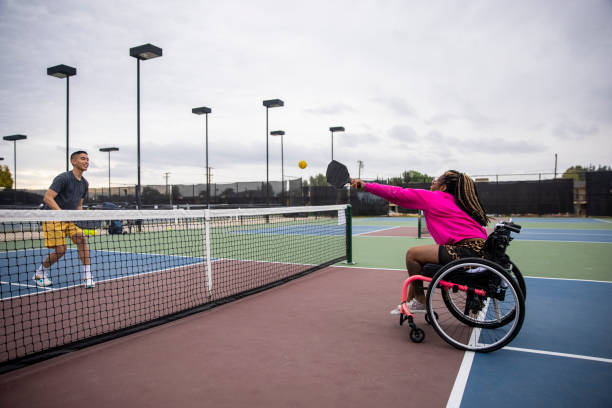 joven negra discapacitada en silla de ruedas jugando pickleball con amigo - wheelchair tennis physical impairment athlete fotografías e imágenes de stock