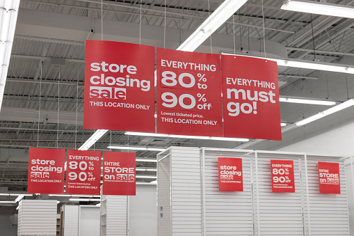 Store Closing and huge discount signs displayed at a soon to be out of business clearance sale. Everything must go at up to 90 percent off sale.