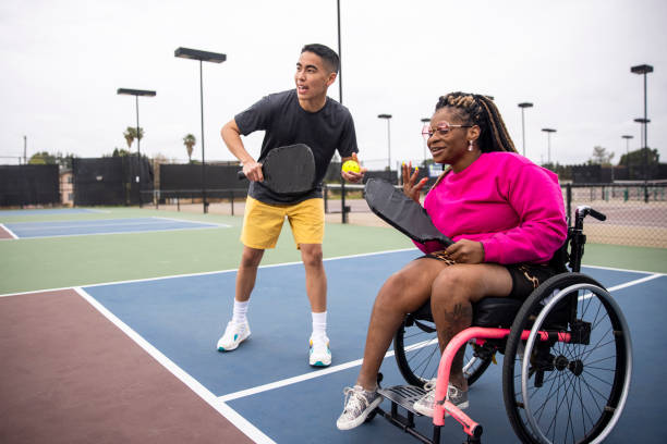 joven negra discapacitada en silla de ruedas jugando pickleball con amigo - wheelchair tennis physical impairment athlete fotografías e imágenes de stock