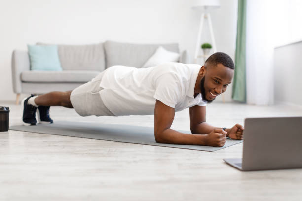 istock Black Man At Laptop Standing In Plank Exercising At Home 1305354983