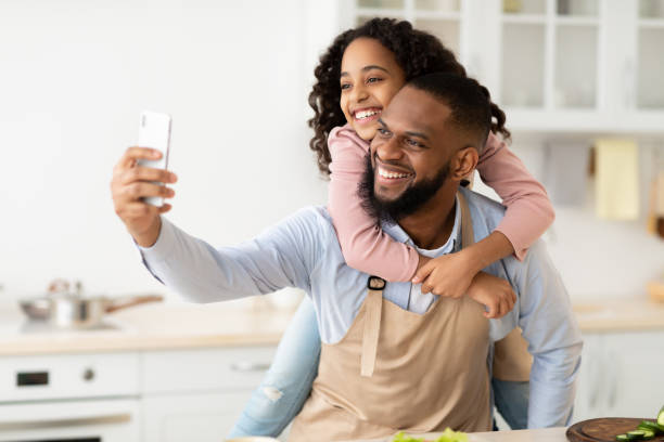istock Cheerful african father taking selfie with cute daughter 1305355548