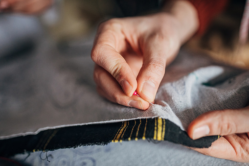 Tailor marking the fabric with sewing pin.