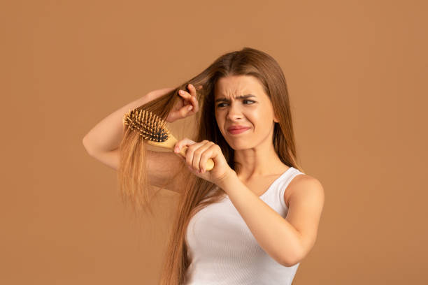Annoyed young woman having problem brushing her long hair on brown studio background. Hairdressing services concept Annoyed young woman having problem brushing her long hair on brown studio background. Irritated millennial lady trying to untangle her disheveled locks. Hairdressing services concept frizzy stock pictures, royalty-free photos & images