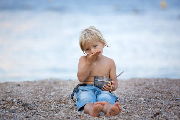 istock Cute boy, child, eating spaghetti on the beach, enjoying dinner 1305356944