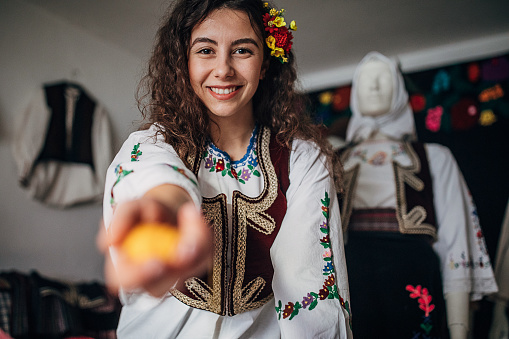 One woman, portrait of a beautiful young female dressed in Serbian national costume. Holding a sewing thread in her hand.