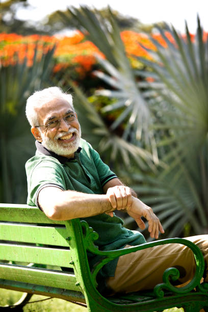 istock Happy senior man spending leisure time sitting at park bench 1305357276