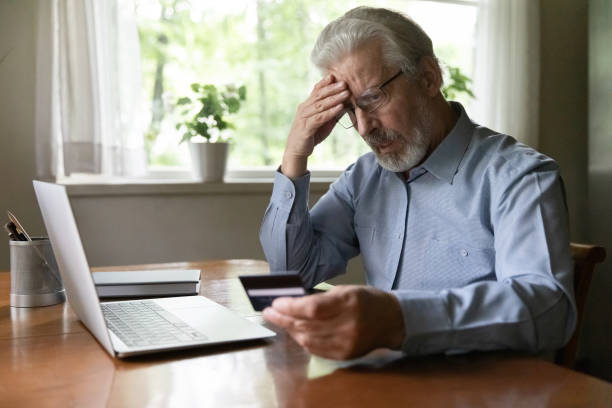 Upset senior man worried about finance safety Upset senior 60 - 70s aged man worried about finance safety data, online payment security. Mature retired grey haired male bank client concerned about problem with credit card, financial fraud threat scammer stock pictures, royalty-free photos & images