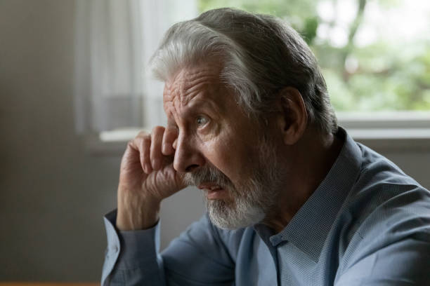 Confused upset old 70s aged man rubbing face and eye