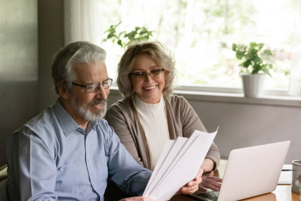 happy older family couple reading and checking financial documents - aging process middle women men imagens e fotografias de stock