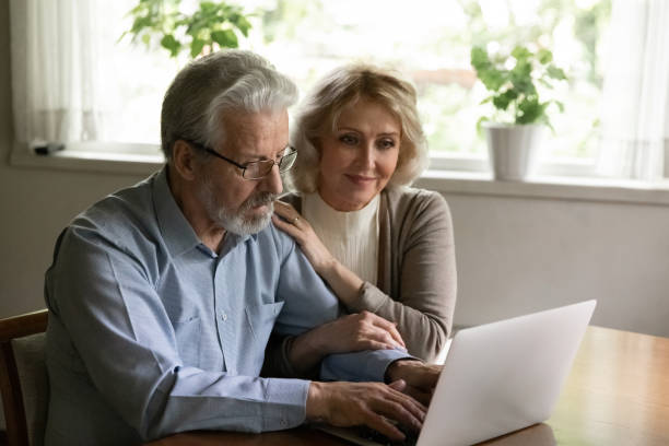 glücklich zuversichtlich reife familie paar mit app auf dem computer - aging process middle women men stock-fotos und bilder