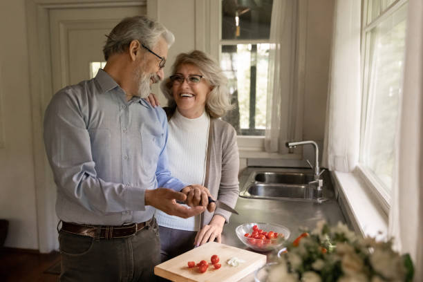 happy middle aged couple of vegans cooking dinner together - aging process middle women men imagens e fotografias de stock