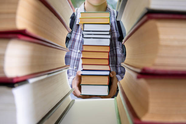 istock A student with a large pile of textbooks stands . 1305362650
