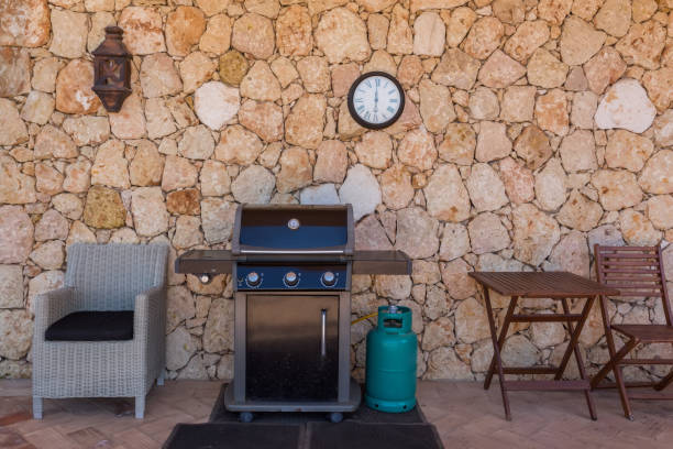 Home gas grill with cylinder, for family holidays and dinners. In the yard near the wall. Home gas grill with cylinder, for family holidays and dinners. In the yard near the wall. High quality photo propane photos stock pictures, royalty-free photos & images