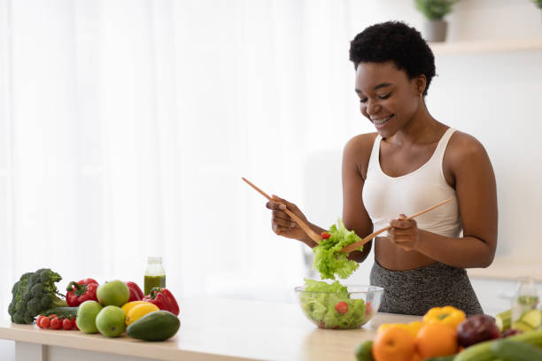 istock Side View Of Black Lady Cooking Vegetable Salad In Kitchen 1305363952