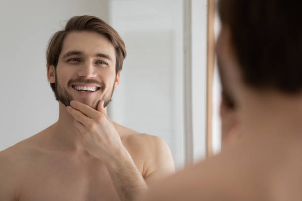 istock Smiling young 30s handsome well-groomed man looking in mirror. 1305364191