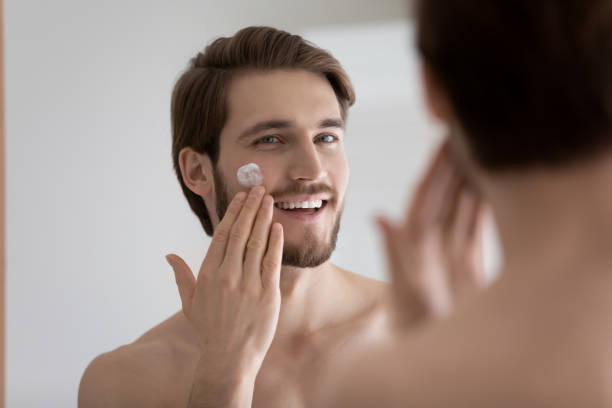 istock Smiling handsome man applying moisturizing creme in bathroom. 1305364239
