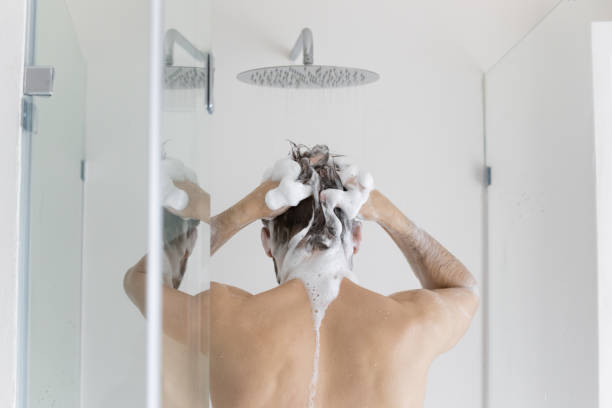 Rear back view young caucasian man taking shower. Rear back view young caucasian man washing hair with moisturizing foamy natural shampoo or gel under runny water, enjoying every day body cleansing routine, taking morning shower in bathroom. dandruff men stock pictures, royalty-free photos & images