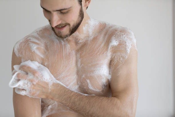 istock Happy young bare man cleaning body with foamy moisturizing gel. 1305364248