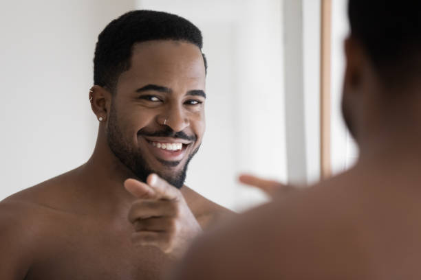 istock Smiling young african ethnicity man pointing finger looking at camera. 1305364259