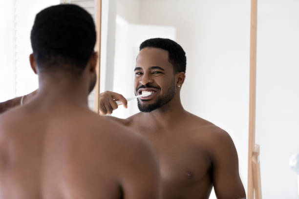 istock Happy young african american bare man brushing teeth. 1305364279