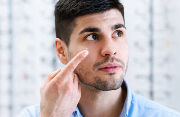 istock Young guy wearing contact eye lenses, looking up 1305364582