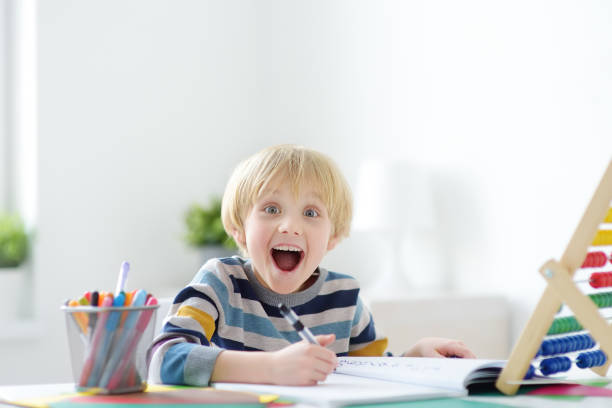 istock Excited elementary school boy doing homework at home. The child is passionate about the learning process. Delighted with what he does. Preparing a preschooler for school. Education 1305366370