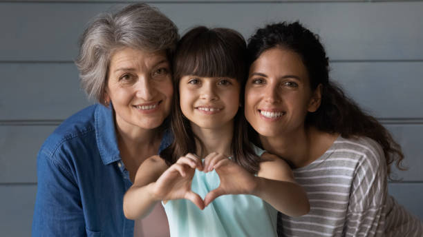 Portrait of happy three generations of Latino women Close up family portrait of happy three generations of Hispanic women pose together show love heart hand gesture. Smiling little Latino girl child with young mother and senior grandmother feel united. heart hands multicultural women stock pictures, royalty-free photos & images