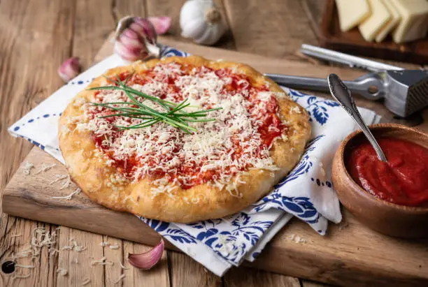 Photo of Classic Hungarian street food Langos, fried bread topped with ketchup, minced garlic and cheese