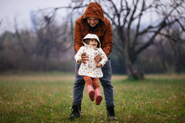 istock Father and daughter flying in a field in rain 1305370321