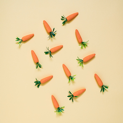 Artificial carrots lay down on pastel background pattern