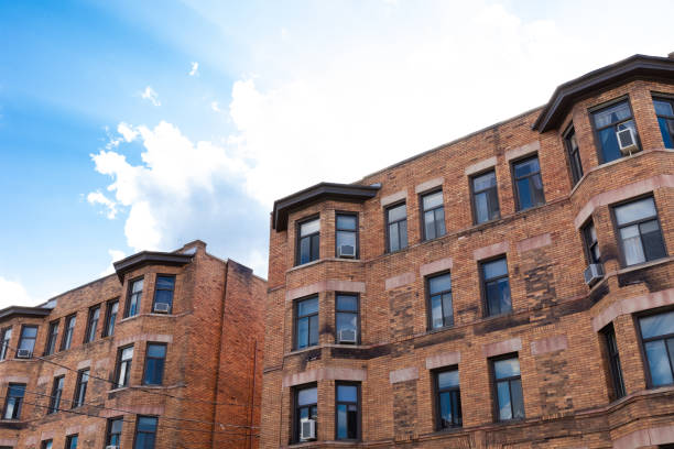 istock Old brick apartment buildings against bright blue sky with clouds 1305383297